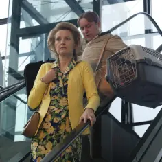 Para podróżuje schodami ruchomymi z pieskiem w transporterze. Scena z filmu "Teściowie 2", gdzie kręcono film.