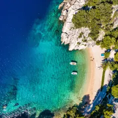 Idealne miejsce na wakacje w Chorwacji: piaszczysta plaża, turkusowa woda i łodzie kołyszące się na falach.