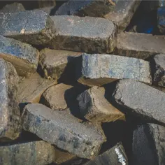 Stos brykietu drzewnego, ciemne, prostokątne kawałki paliwa.