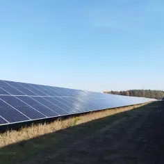 Panele fotowoltaiczne i wiatraki na tle błękitnego nieba. Kto płaci podatek od nieruchomości przy umowie dzierżawy?