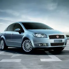 Elegancki, błękitny Fiat Linea na tle miejskiego krajobrazu.