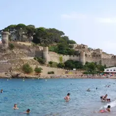 Piękna plaża w Hiszpanii, z zamkiem na wzgórzu. Idealne miejsce na wakacje, zastanawiasz się, ile się leci z Polski do Hiszpanii?