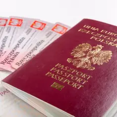 Czerwony paszport polski z godłem orła i kilka dowodów osobistych leżą obok siebie.