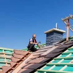 Pracownik układa dachówki na konstrukcji dachu dwuspadowego 200m2. Szacowany koszt dachu dwuspadowego 200m2.