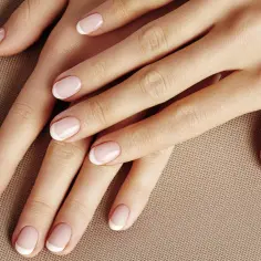 Dłonie z klasycznym, kolorowym frenchem. Delikatny róż i biel tworzą elegancki manicure.