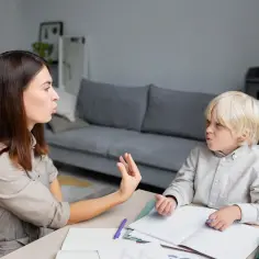Terapeutaka pokazuje dziecku ćwiczenia artykulacyjne. Opinia z poradni pomoże w dalszej pracy.