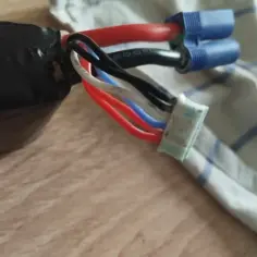 Czerwony kabel to plus. Widać go obok niebieskich złączek i białego złącza z kilkoma przewodami.