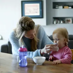 Niania wyciera buzię dziecka. Zastanawiasz się, ile biorą nianie za godzinę?