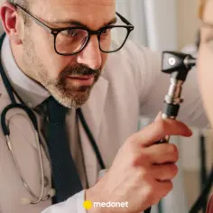 Lekarz bada ucho pacjentki otoskopem. Betaserc na co pomaga? Właściwa diagnoza to pierwszy krok do ulgi.