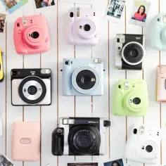 Kolekcja kolorowych aparatów Instax, jak z instax, ułożona na białym tle, otoczona odbitkami.