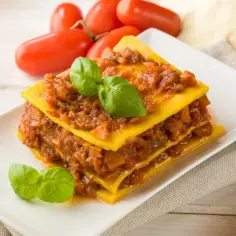 Pyszna, domowa lasagne z sosem bolońskim i listkami bazylii. Idealna porcja, by zaspokoić głód.