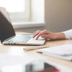 Praca biurowa wymaga regularnych badań. Kobieta pracuje przy laptopie, obok notatnik i długopis.