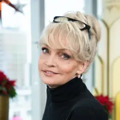 Adrianna Biedrzyńska z okularami na blond włosach, uśmiechnięta, w czarnym golfie.