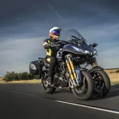 Kierowca na motocyklu Yamaha Niken GT przemierza wiejską drogę.