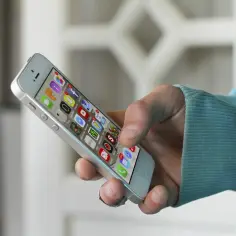 Dłoń trzyma smartfon z ikonami aplikacji. Szybkie zakupy? Wystarczy tap to pay!