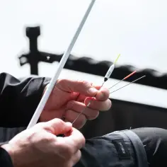Wędkarz przygotowuje zestaw z gruntomierzem i spławikiem.