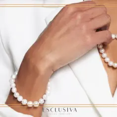 Dłoń dotyka naszyjnika z pereł, który wraz z bransoletką tworzy elegancki komplet.