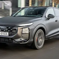 Matowy, ciemnoszary q3 audi pędzi po drodze, jego reflektory LED świecą jasno.
