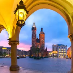 Kraków, Rynek Główny z Sukiennicami i Kościołem Mariackim o zmierzchu, widziany przez arkady.