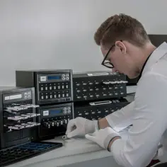 Mężczyzna w białej koszuli i rękawiczkach obsługuje kopiarkę pendrive'ów.