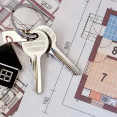 Klucze do mieszkania na planach architektonicznych. Dowiedz się, jak sprawdzić zarząd wspólnoty mieszkaniowej, zanim podejmiesz decyzję o zakupie.
