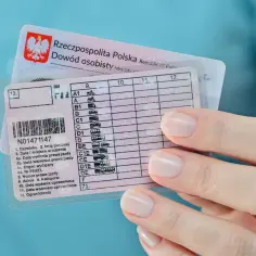 Polskie prawo jazdy z kategorią B2, obok dowodu osobistego. Kobieta trzyma dokumenty.