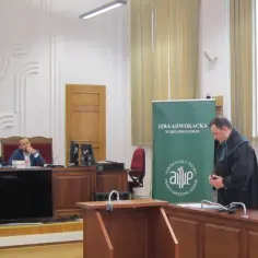 Sąd w Zielonej Górze: sędziowie przy stole, prawnik w todze i zielony baner Izby Adwokackiej.
