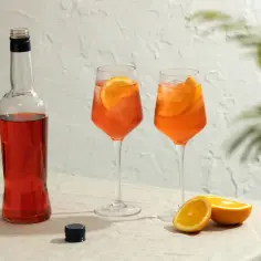 Butelka Aperolu i dwa drinki z pomarańczą. Idealne na lato, gdy chcesz wiedzieć, jak zrobić prosecco z aperolem.