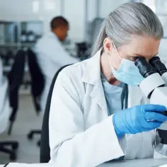 Naukowcy w laboratorium badają nowy wariant koronawirusa pod mikroskopem, pracując nad szczepionką.