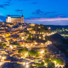 Toledo nocą, jedno z najpiękniejszych miejsc Hiszpanii. Zamek Alcázar góruje nad oświetlonym miastem i rzeką Tag.