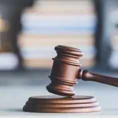 Drewniany młotek sędziowski na tle stosu ksiąg. Symbol sprawiedliwości i pracy asesor sądowy.