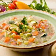 Aromatyczna zupa na rosole z mnóstwem warzyw: marchewką, cukinią, groszkiem i ziemniakami.