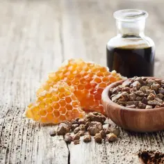 Propolis działanie: miód, plastry miodu, propolis w ziarnach i nalewka na drewnianym tle.