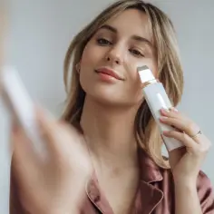 Kobieta wykonuje zabieg **peeling kawitacyjny** na twarzy, używając nowoczesnego urządzenia.