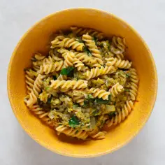 Fusilli z porem i zielonymi ziołami w żółtej misce. Pyszny makaron z porem, idealny na szybki obiad.