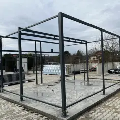 Konstrukcja pod projekt garażu z płyty warstwowej. Widać stalowy szkielet, materiały budowlane i plac budowy.