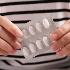 Dłonie trzymają opakowanie tabletek. Czy można przerwać antybiotyk? To pytanie nurtuje wiele osób.