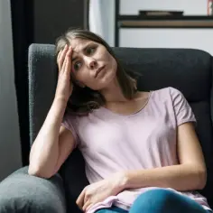 Zmartwiona kobieta w fotelu, zastanawia się, ile trwa odzyskanie dziecka z rodziny zastępczej.