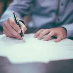 Dłoń pisze piórem na papierze. Decyzja o porzuceniu pracy zapadła.
