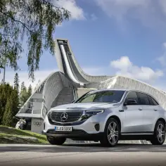 Srebrny Mercedes EQC przed skocznią narciarską w Oslo. Elektryczna jazda w otoczeniu sportowej historii.