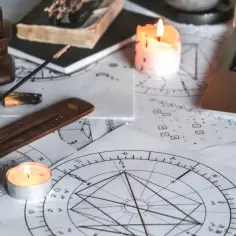 Astrologiczne wykresy, świece i kadzidełko tworzą atmosferę do rozważań, jak obliczyć ascendent bez godziny urodzenia.