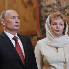 Władimir Putin w garniturze i z żoną w białej chuście i stroju, z naszyjnikiem z pereł.