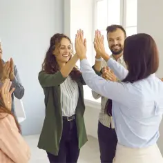 Zespół świętuje sukces, dając sobie piątki. Inspiracja: jak motywować pracowników bez podwyżki 7 sprawdzonych sposobów.