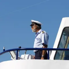 Kapitan na mostku statku, zastanawia się, ile zarabia marynarz.
