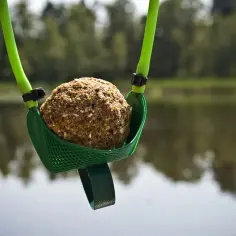 Proca zanętowa z kulką zanęty nad wodą.