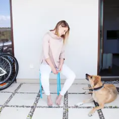 Katarzyna Kędzierska, w młodym wieku, siedzi na krześle, a jej pies leży obok. Obok stoi rower.