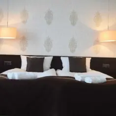 Przytulne łóżko hotelowe z dwoma lampkami. Zastanawiasz się, od ilu lat można wynająć hotel? Zazwyczaj od 18 lat.