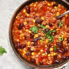 Prawdziwa zupa meksykańska z fasolą, kukurydzą i mielonym mięsem, ozdobiona papryczkami chili i natką pietruszki.
