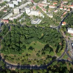 Widok z lotu ptaka na zielony park otoczony drogami, z budynkami mieszkalnymi w tle. To największe rondo w Polsce, tętniące życiem.