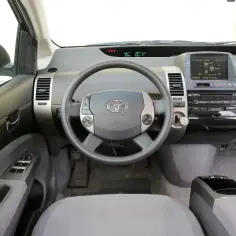 Wnętrze toyoty prius 2. Kierownica z przyciskami, ekran multimedialny i panel radia.